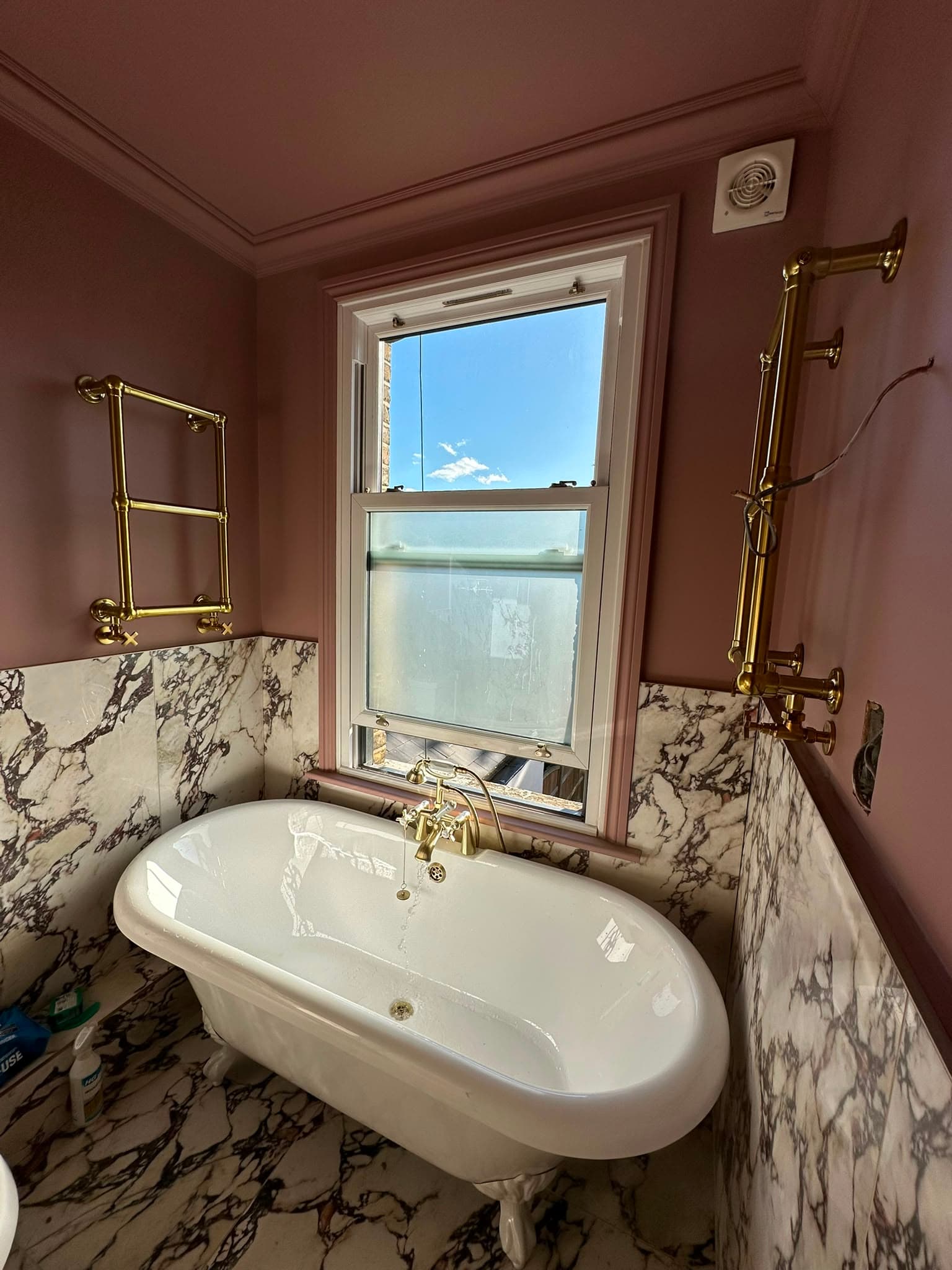 Roll-top claw-foot bath with Arabescato marble tiles and polished brass fittings