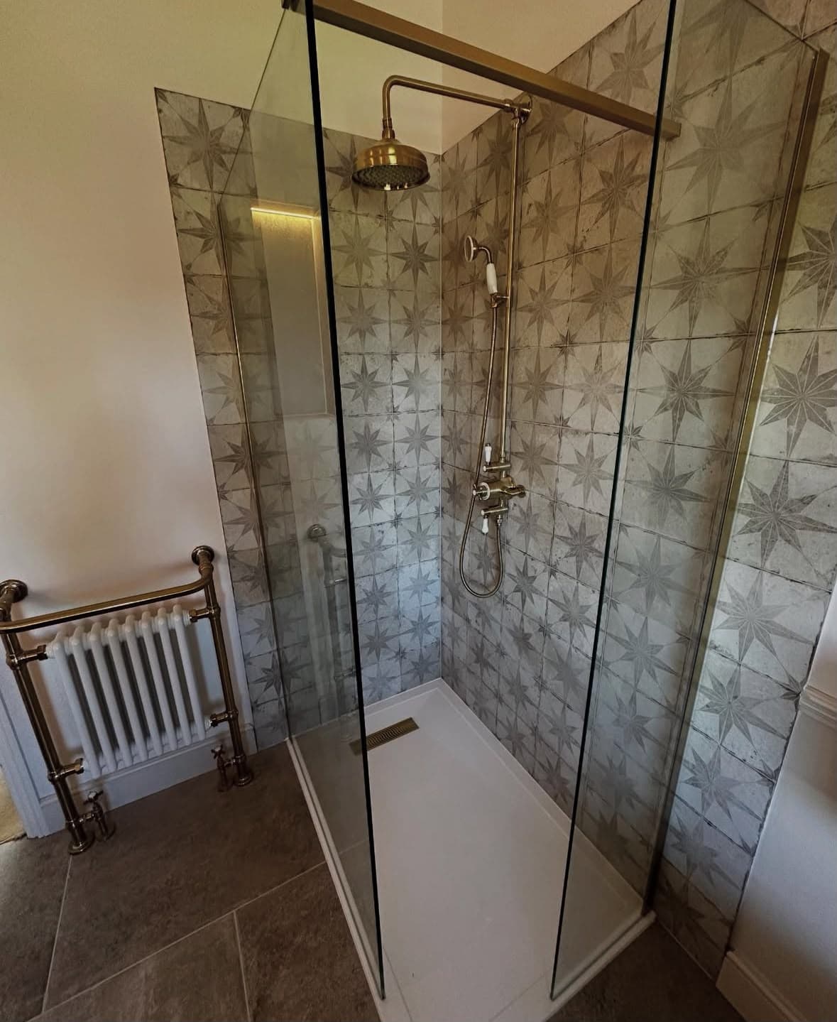Artisan star-pattern tiled shower room with traditional brass shower column and gold heated towel rail