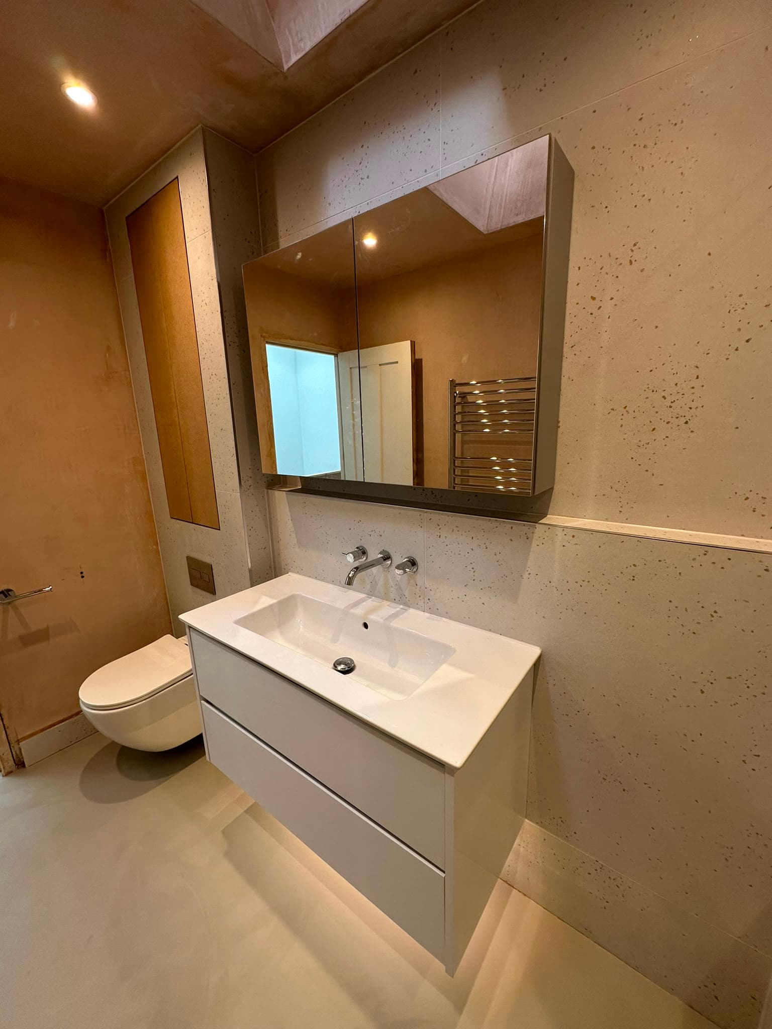 Floating white vanity unit with mirrored cabinet, wall-mounted taps and wall-hung WC