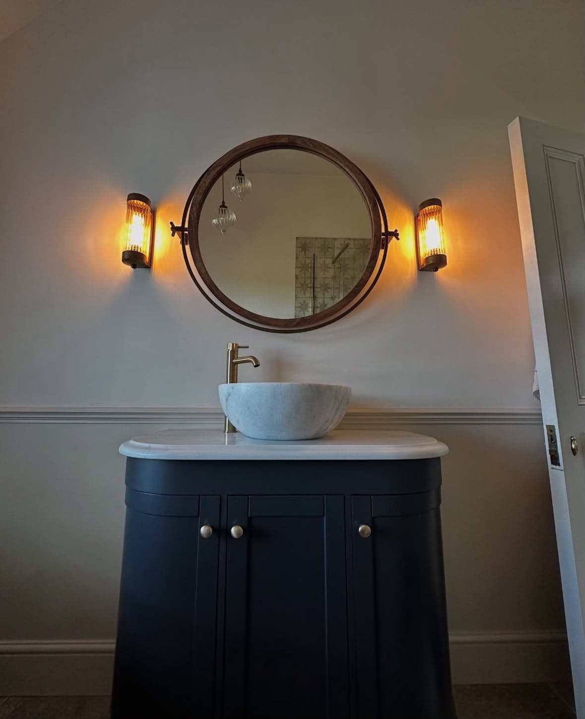 Bespoke bathroom design — dark vanity with marble vessel sink and warm lighting